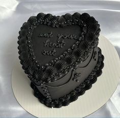 a black heart shaped cake on top of a white plate