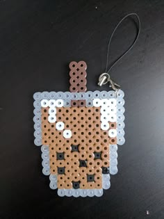 an ornament made out of plastic beads with a cat in the middle on a black surface