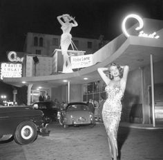 an old photo of a woman in front of a building with a sign on it