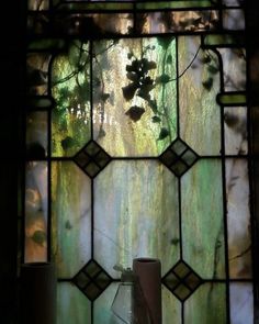 a vase sitting in front of a stained glass window with ivys growing on it