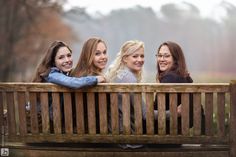 four women are sitting on a wooden bench