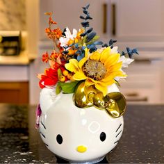 a hello kitty vase with sunflowers and other flowers in it on a kitchen counter