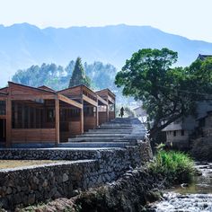 a row of houses next to a river with mountains in the backgrouds