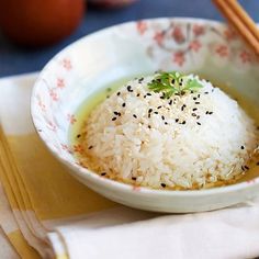 a white bowl filled with rice and chopsticks on top of a cloth napkin