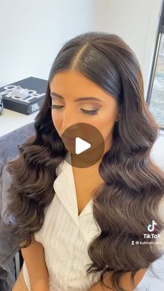 an image of a woman with long wavy hair in front of the camera and wearing a white shirt