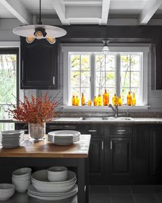 a kitchen with black cabinets and white plates on the counter top next to an island