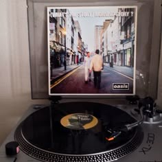 an old record player is sitting on top of the turntable in front of a poster