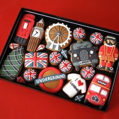 an assortment of decorated cookies in a black box on a red tablecloth with the british flag