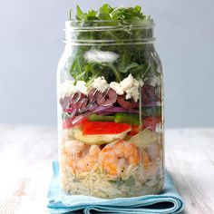 a mason jar filled with pasta, shrimp and veggies