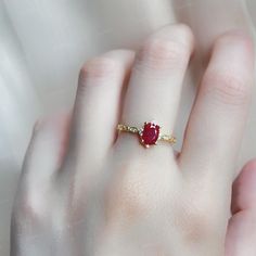 a woman's hand with a ring on it and a red stone in the middle