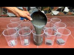 a person pouring cement into cups on the ground