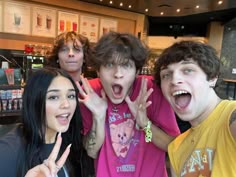 three young people posing for the camera with their hands in the air and one holding up two fingers