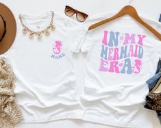 two t - shirts with the words in my mermaid bras on them next to hats and sunglasses