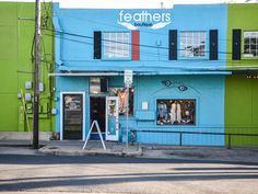 a blue and green building with black shutters on the front, next to a street corner