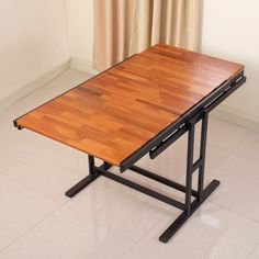 a wooden table sitting on top of a hard wood floor next to a curtained window