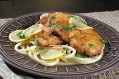 a plate with chicken, noodles and lemon slices