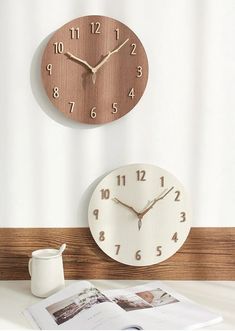 a clock that is on the wall next to a coffee cup and magazine with an open book in front of it