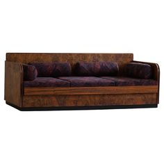 a couch that is made out of wood and has purple fabric on the backrest