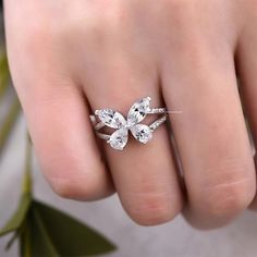 a woman's hand with a diamond ring on top of her finger and an open flower