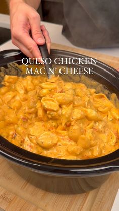 a person cooking macaroni and cheese in a crock pot with the words, queso chicken mac n'cheese