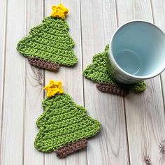 crocheted christmas tree coasters with yellow and brown flowers on them next to a cup of water