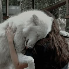 a woman hugging a white wolf in her arms