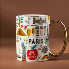 a coffee mug with the words paris printed on it, sitting on a brown surface