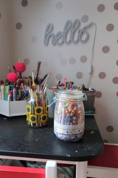 there is a jar full of crayons on the table next to some pens and pencils