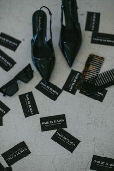 a pair of black high heel shoes sitting on top of a floor next to business cards