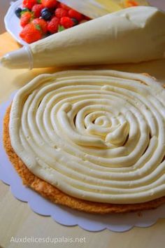 a cake with white frosting and fruit in the middle on a plate next to it