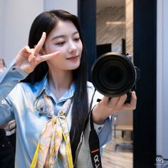 a woman is holding up her camera and making the peace sign