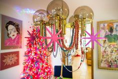 a chandelier hanging from the ceiling in front of a christmas tree with pink stars