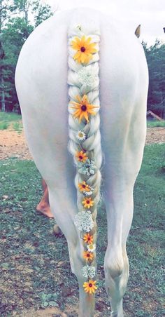 the back end of a white horse with yellow flowers on it's head and tail