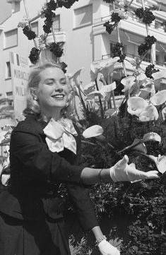 a black and white photo of a woman in front of flowers