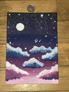 a piece of art with clouds and stars painted on it, next to a penny