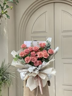 a large bouquet of pink roses in front of a door