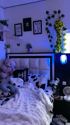 a bed with black and white comforter, stuffed animals on the headboard and pillows