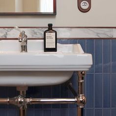 a white sink sitting under a bathroom mirror next to a faucet mounted on a wall