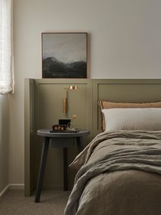 a bed sitting next to a night stand with a lamp on it's side