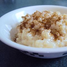 a white bowl filled with mashed potatoes covered in cinnamon sprinkles and powdered sugar