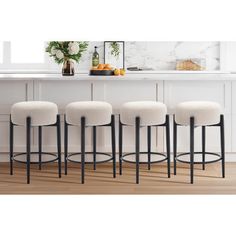 four white stools sitting in front of a counter