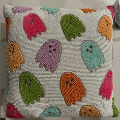 a decorative pillow with many different colored ghost faces on it's front and back