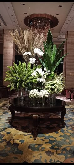 a table with flowers and greenery on it in a hotel lobby or sitting area