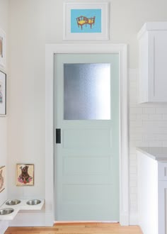 a white door in a room with pictures on the wall and dog bowls below it