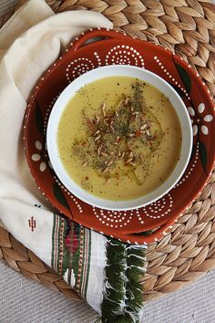 a bowl of soup is sitting on a red and white plate next to a napkin