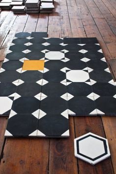 a black and white tile floor with yellow square in the middle on top of it