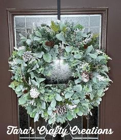 a wreath with pine cones and greenery on the front door