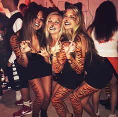 three girls dressed in tiger costumes posing for the camera with their hands painted like cats