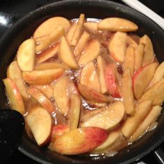 apple slices are being cooked in a pan on the stove top with liquid over them