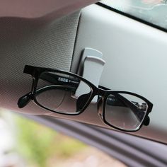 a pair of black glasses sitting on top of a window sill in a car